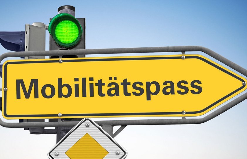 Verkehrsschild mit Bezeichnung "Mobilitätspass", im Hintergrund gründe Ampel, im Vordergrund Vorfahrtsschild 