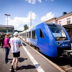 Einfahrender Zug Bahnhof, wartende Passagiere auf Bahngleis