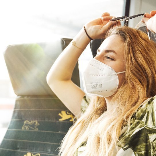 Frau mit FFP2-Maske auf bwegt Bahnsitz 