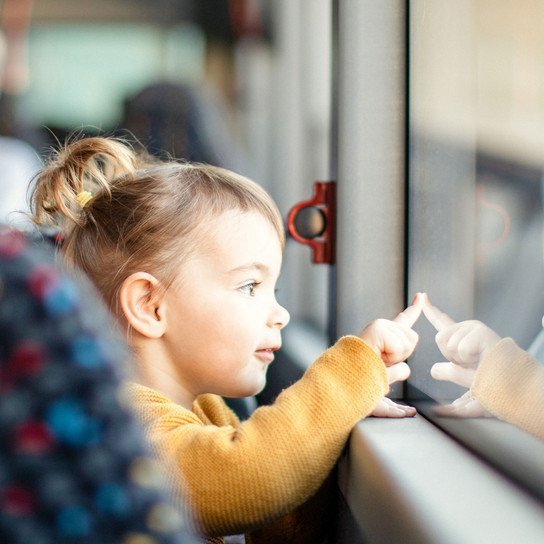 Kleinkind schaut aus Busfenster raus