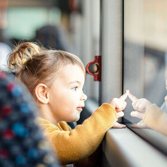 Kleinkind schaut aus Busfenster raus
