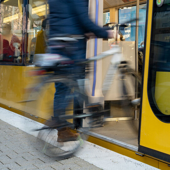 Person mit Fahrrad am Bahnsteig, steigt in S-Bahn ein
