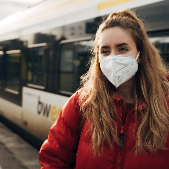 Frau mit FFP2 Maske vor bwegt Bahn