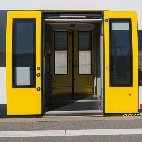 bwegt Zug mit offenen Türen an Bahnsteig 
