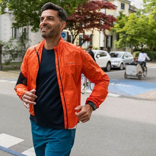Jogger überquert Straße, im Hintergrund Fahrradfahrer:innen