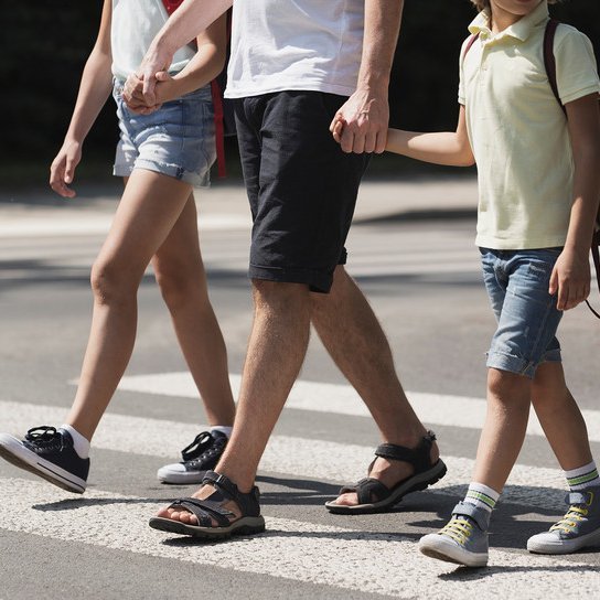 Mann mit Kindern überquert Zebrastreifen