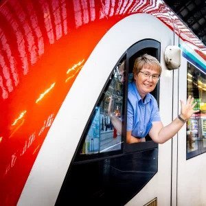 Aus Zugfenster winkende Zugführerin