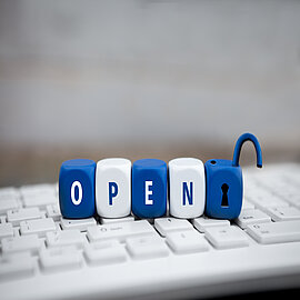 Würfel mit dem Wort Open auf Tastatur liegend
