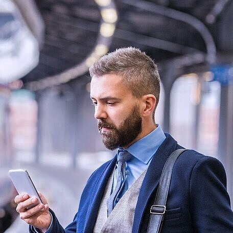Mann auf Bahngleis guckt auf Smartphone